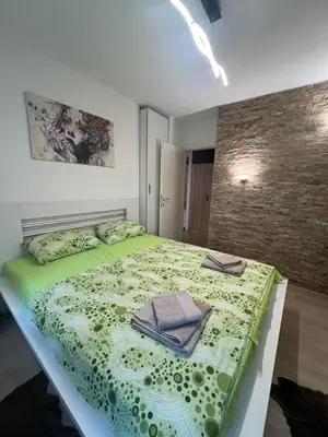 a bedroom with a green bed with towels on it at Stan u centru grada in Niš