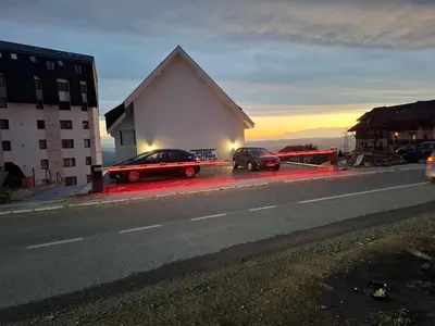 two cars parked next to a building on the side of a road at Apartman Black Star Kop in Kopaonik