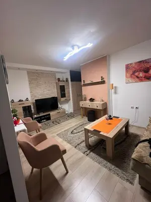 a living room with a table and a living room with a couch at Stan u centru grada in Niš