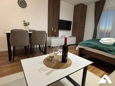 a living room with a bottle of wine and glasses on a table at Apartman Oliver in Kopaonik