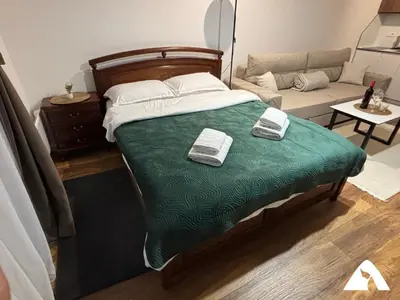a bedroom with a bed with green sheets and a couch at Apartman Oliver in Kopaonik