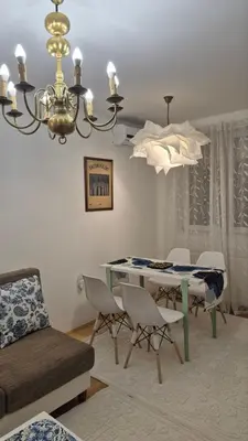 a living room with a table and chairs and a chandelier at City Notes apartment in Niš