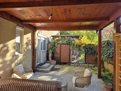 an outdoor patio with chairs and a wooden pergola at City Notes apartment in Niš