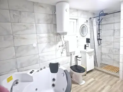 a bathroom with a white tub and a toilet at Black House Spa