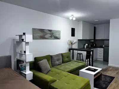 a living room with a green couch and a kitchen at Cute Comfort Apartments in Niš