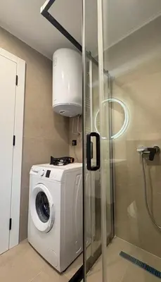 a washing machine in a bathroom with a shower at Cute Comfort Apartments in Niš