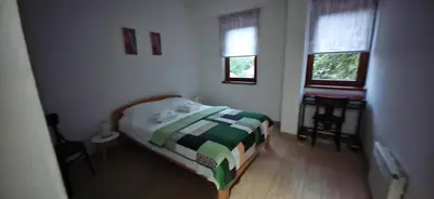 a small bedroom with a bed and two windows at Apartman Besu in Vrnjačka Banja