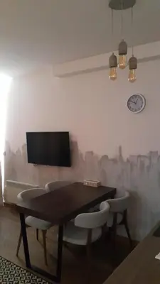 a dining room table with chairs and a tv on a wall at Nevena and Spa apartmans in Bukorovac