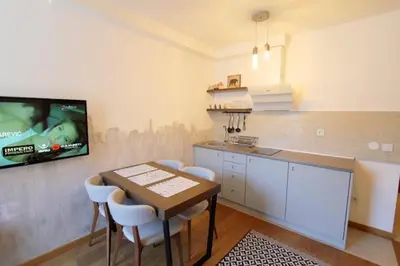 a kitchen with a table and a tv on a wall at Nevena and Spa apartmans in Bukorovac