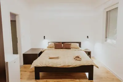 a white bedroom with a large bed and a window at Gallus Inn in Aleksinac