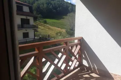 a wooden balcony with a view of a building at Apartman Foka Spa in Brzeće