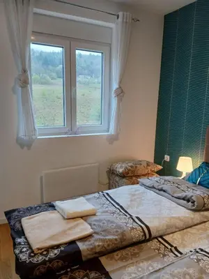 two beds in a room with a window at Apartman Pogled Lux - Green Hill Sokobanja in Soko Banja