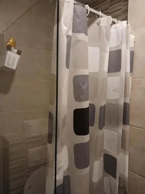 a shower curtain in a bathroom with a toilet at Apartman Pogled Lux - Green Hill Sokobanja in Soko Banja
