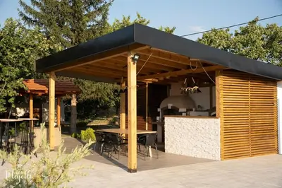 a wooden pavilion with a table and chairs under it at Vila Belgijska pruga in Zaječar
