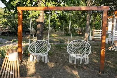 two white chairs on a swing in a park at Vila Belgijska pruga in Zaječar