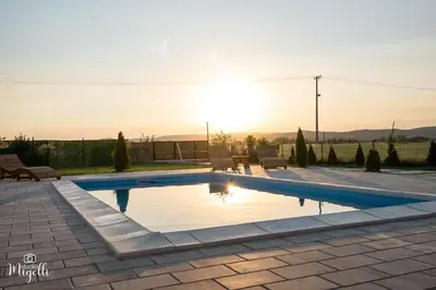 a swimming pool with a sunset in the background at Vila Belgijska pruga in Zaječar