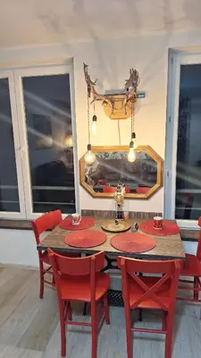 a dining room with a table and red chairs at Play Apartments in Paraćin