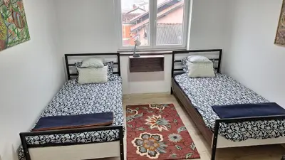 two beds in a room with a window and a rug at Play Apartments in Paraćin