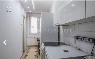 a white kitchen with a stove top oven next to a window at Stan in Niš