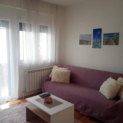 a living room with a purple couch and a coffee table at NoVa apartman - stan na dan in Vranje