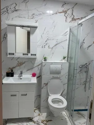 a white bathroom with a toilet and a sink at Mija in Vrnjačka Banja