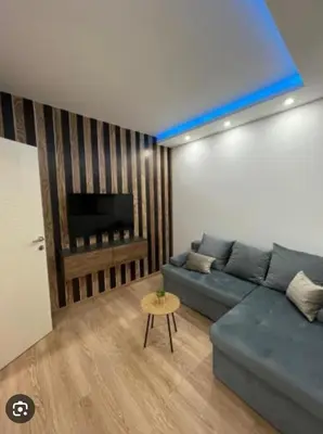 a living room with a blue couch and a piano at Apartman Brankovic in Jagodina
