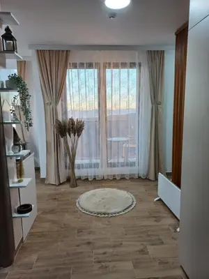 a living room with a large window and a rug at Planinski san in Kopaonik