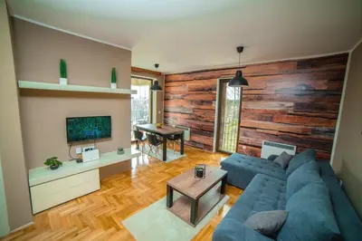 a living room with a blue couch and a wooden wall at Vrnjacka Bajka in Vrnjačka Banja