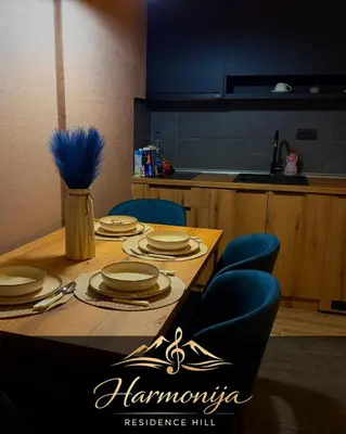 a dining room table with plates and blue chairs at Harmonija Residence Hill 01 in Kopaonik