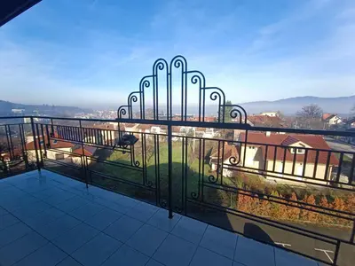 a balcony with a view of a park with a bench at Apartman Paunov Breg in Vrnjačka Banja
