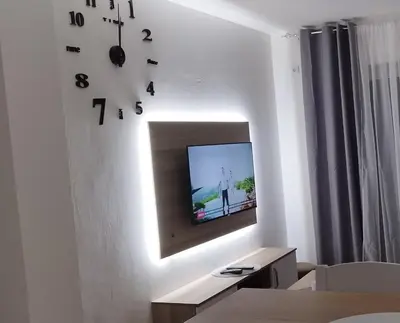 a living room with a tv and a clock on the wall at Apartman Ognjen Vrnjacka Banja in Vrnjačka Banja