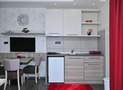 a kitchen with white cabinets and a table with a tv at K8 Milmari in Kopaonik