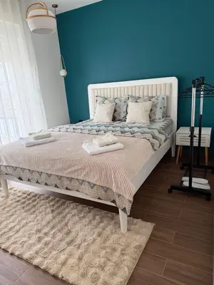 a bedroom with a white bed with a blue wall at Zira apartman in Vranje