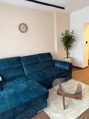 a living room with a blue couch and a glass table at Zira apartman in Vranje