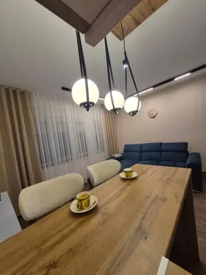 a dining room with a wooden table with two cups on plates at Zira apartman in Vranje