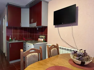 a kitchen with a table and a television on the wall at Urban Apartmens 5 in Jošanička Banja