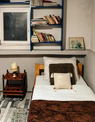 a bedroom with a bed and a window and shelves at Apartman Poirot in Kuršumlija