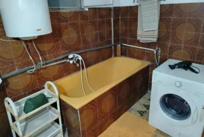 a bath tub with a washing machine in a bathroom at Apartman Poirot in Kuršumlija
