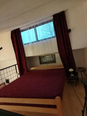 a bedroom with a red bed and a window at Apartman 
