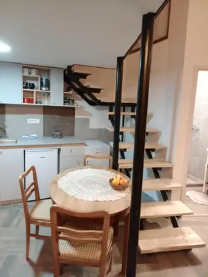 a kitchen and dining room with a table and a spiral staircase at Apartman 