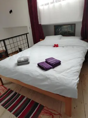 a white bed with two purple towels on it at Apartman 
