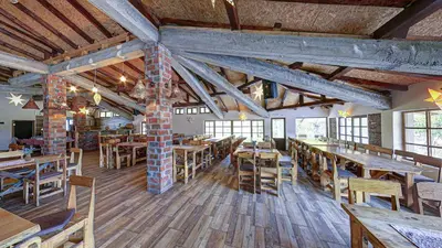 a restaurant with wooden tables and chairs in a room at Srna Etno Selo - Hotel i Restoran in Inovo