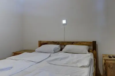 two beds in a room with white sheets and pillows at Srna Etno Selo - Hotel i Restoran in Inovo