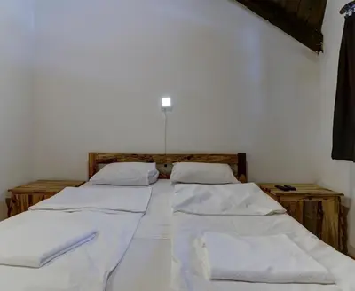 two beds in a room with white sheets at Srna Etno Selo - Hotel i Restoran in Inovo