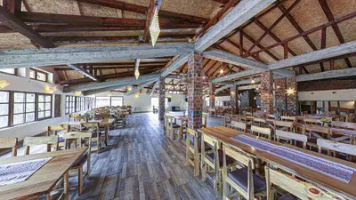 an empty restaurant with wooden tables and chairs at Srna Etno Selo - Hotel i Restoran in Inovo