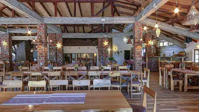 a restaurant with wooden tables and chairs and brick walls at Srna Etno Selo - Hotel i Restoran in Inovo