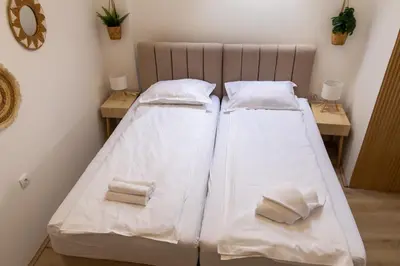 two beds in a room with white sheets and towels at Urban Nest Apartments in Niš