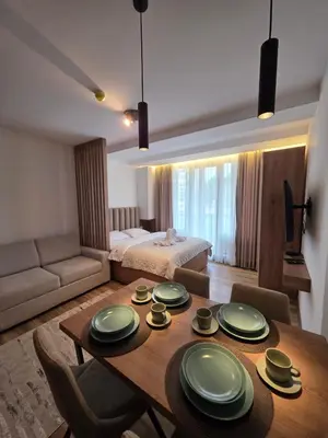 a living room with a dining room table and a bedroom at E&E Apartman in Kopaonik