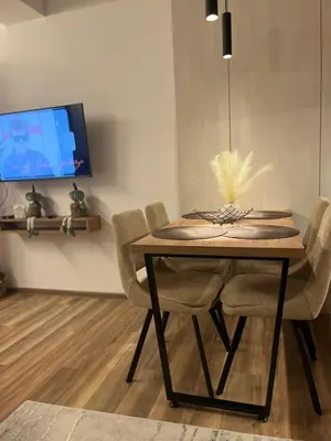 a dining room table with chairs and a tv at E&E Apartman in Kopaonik