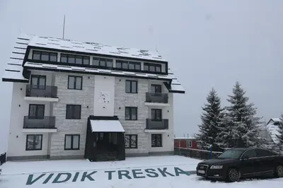 a building with a car parked in front of it at Apartmani Vidik,Treska in Kopaonik